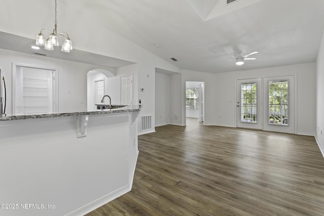 11213 Harbour Vista Cir, Saint Augustine, FL 32080 - unfurnished living room with dark wood-style flooring, visible vents, arched walkways, ceiling fan with notable chandelier, and vaulted ceiling