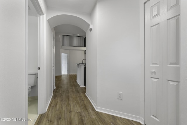 11213 Harbour Vista Cir, Saint Augustine, FL 32080 - hallway featuring baseboards, arched walkways, and wood finished floors