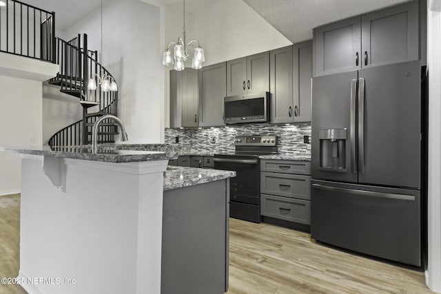 11213 Harbour Vista Cir, Saint Augustine, FL 32080 - kitchen with appliances with stainless steel finishes, stone countertops, gray cabinets, a peninsula, and tasteful backsplash