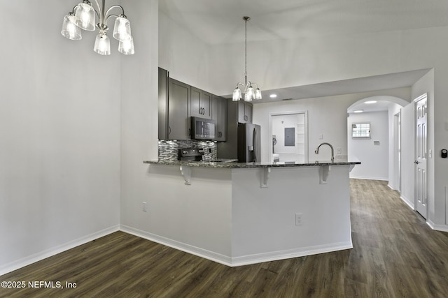 11213 Harbour Vista Cir, Saint Augustine, FL 32080 - kitchen featuring dark stone countertops, a kitchen breakfast bar, dark wood finished floors, a notable chandelier, and stainless steel appliances
