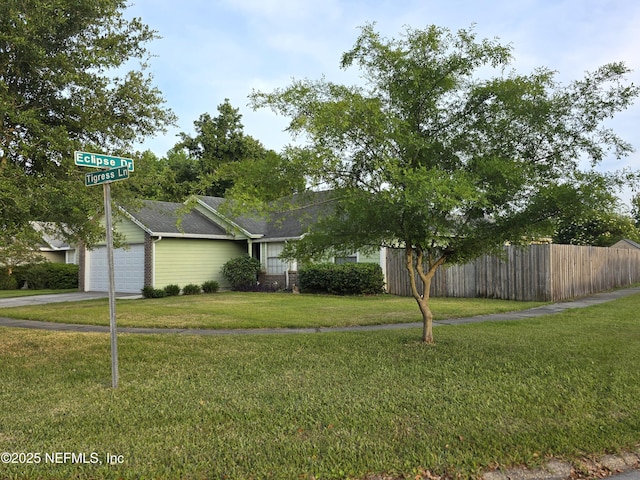 exterior space with a front lawn, driveway, roof with shingles, an attached garage, and fence