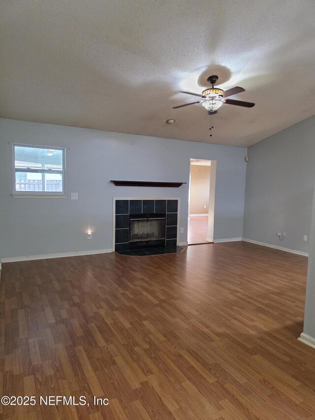 unfurnished living room featuring wood finished floors, a ceiling fan, and a textured ceiling