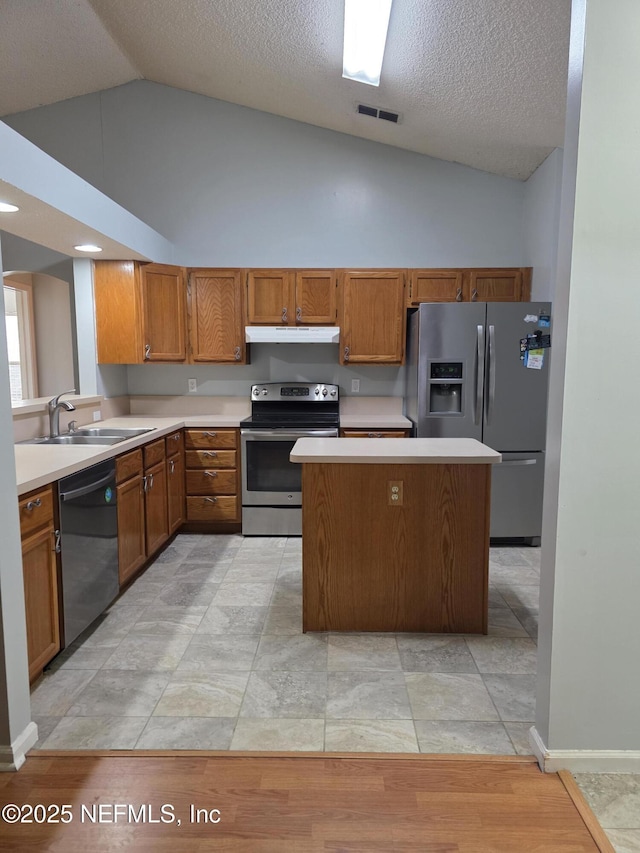 kitchen featuring appliances with stainless steel finishes, light countertops, under cabinet range hood, and a sink