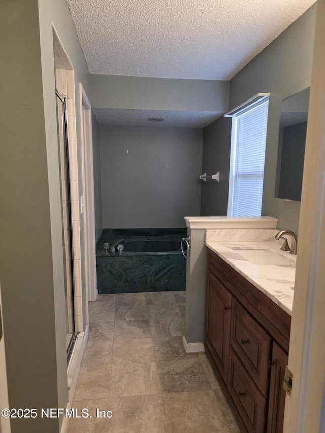 full bath with a textured ceiling, vanity, a shower stall, and a bath