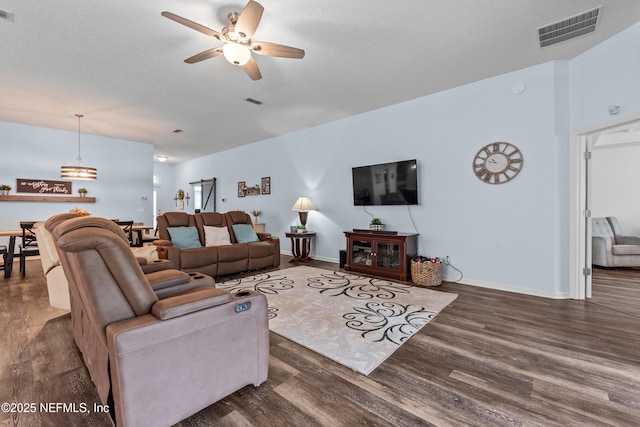 living area featuring baseboards, a ceiling fan, wood finished floors, and visible vents