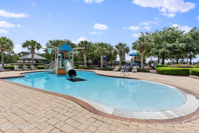 pool with a patio, fence, playground community, and a water slide