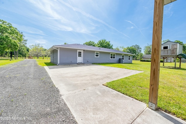 back of property featuring a lawn, a shingled roof, and driveway
