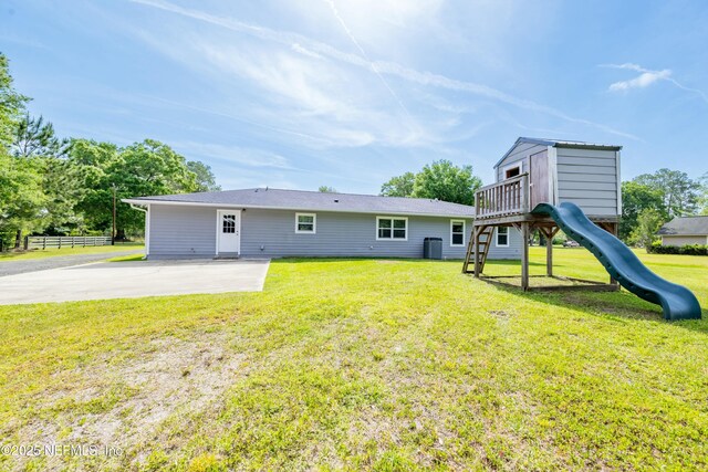 back of property featuring a yard and a playground