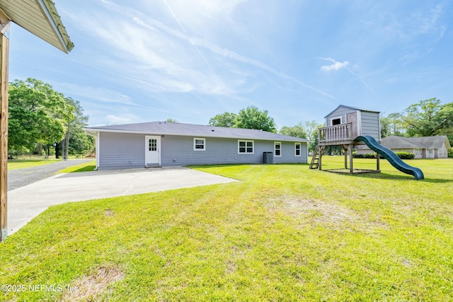 back of house featuring a lawn, a patio, and a playground