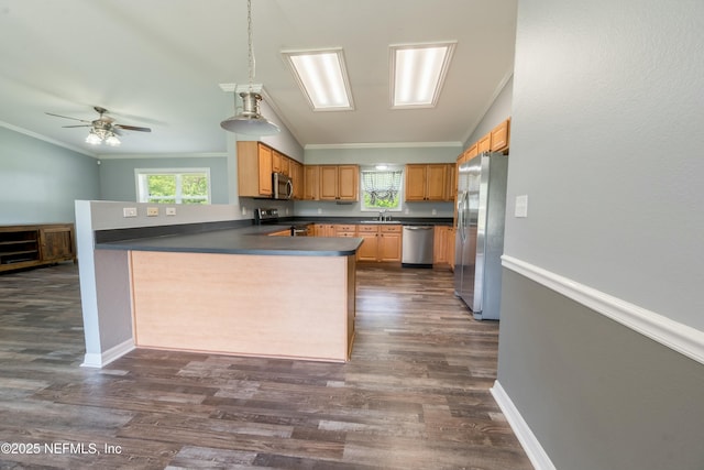 kitchen featuring stainless steel appliances, a peninsula, a sink, dark countertops, and ornamental molding