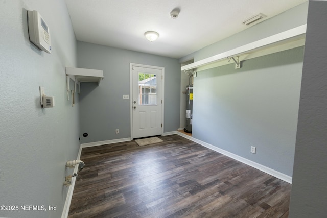 clothes washing area featuring water heater, wood finished floors, visible vents, hookup for an electric dryer, and baseboards