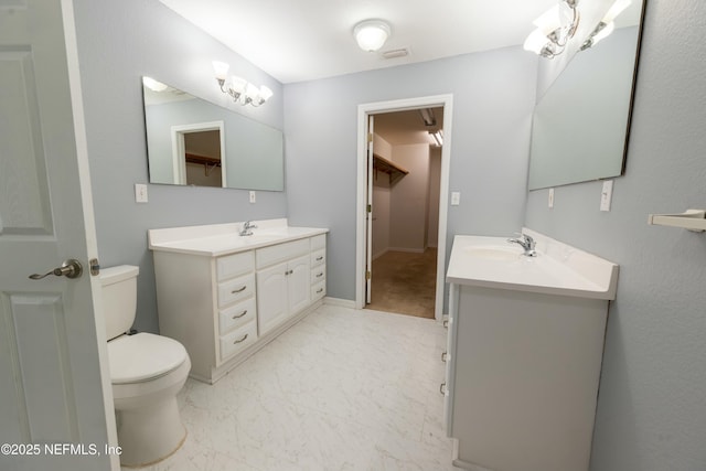 full bathroom featuring a sink, marble finish floor, toilet, two vanities, and visible vents