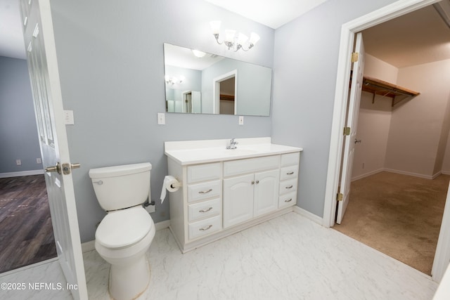 bathroom featuring toilet, baseboards, marble finish floor, vanity, and a walk in closet