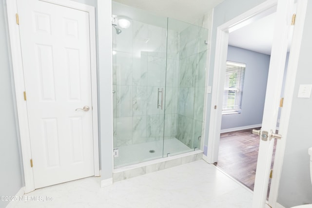 full bathroom with baseboards, toilet, and a marble finish shower