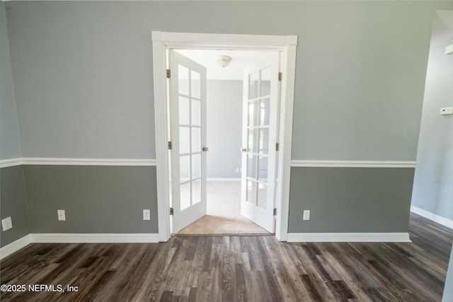 empty room with baseboards, french doors, and dark wood-style floors