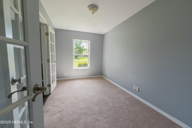 empty room with carpet floors, baseboards, and french doors