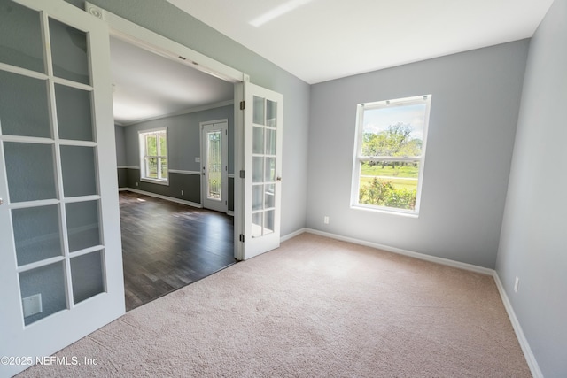 carpeted spare room featuring baseboards and french doors
