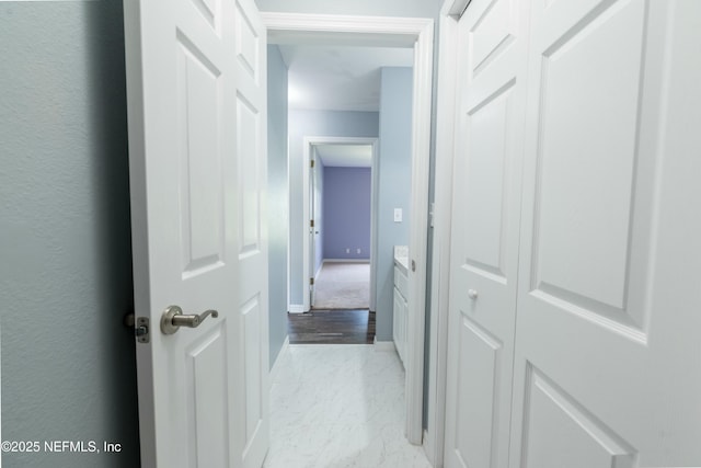 corridor with marble finish floor and baseboards