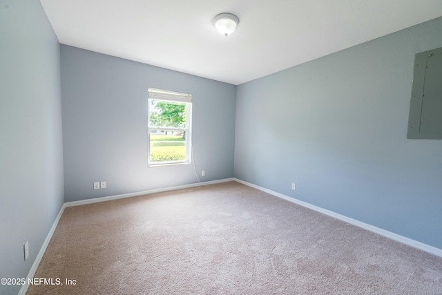 empty room with electric panel, baseboards, and carpet