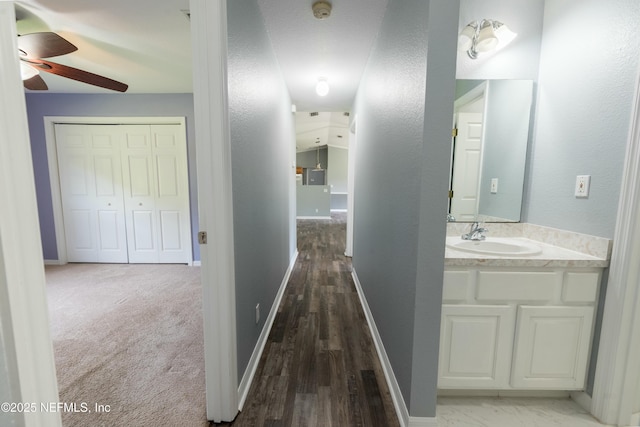 hallway with baseboards and a sink