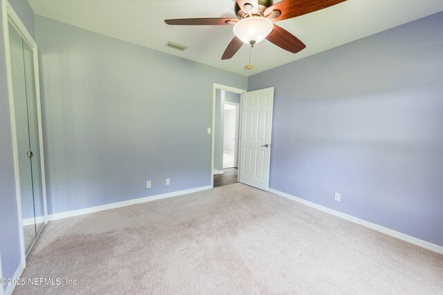 unfurnished bedroom with baseboards, visible vents, carpet, and ceiling fan