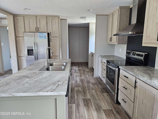 kitchen featuring a sink, a textured ceiling, appliances with stainless steel finishes, and wall chimney range hood
