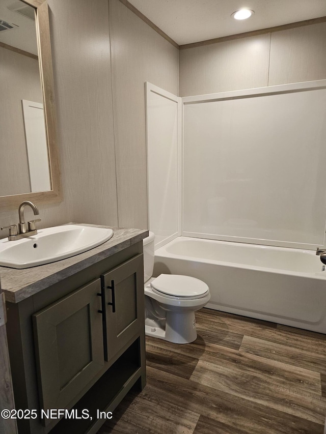 bathroom with crown molding, wood finished floors, vanity, toilet, and visible vents