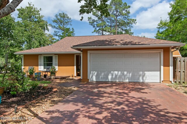 ranch-style home featuring stucco siding, fence, a garage, driveway, and roof with shingles