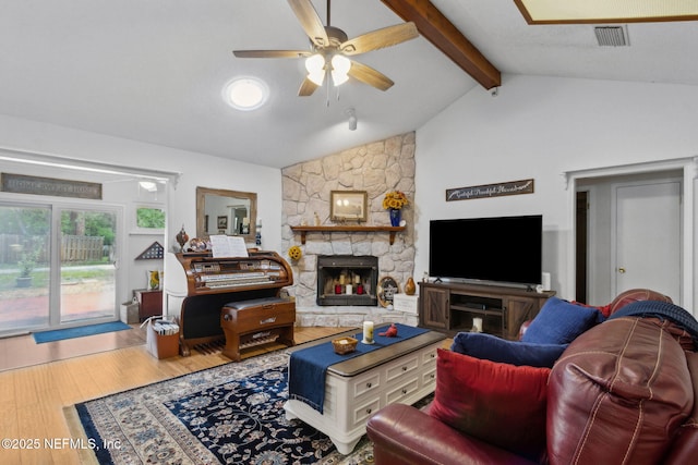 living area with visible vents, lofted ceiling with beams, a fireplace, wood finished floors, and a ceiling fan