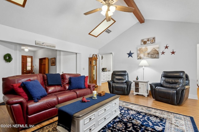 living area featuring visible vents, beamed ceiling, a ceiling fan, and light wood finished floors