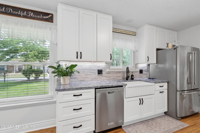 kitchen with backsplash, a sink, white cabinetry, and stainless steel appliances