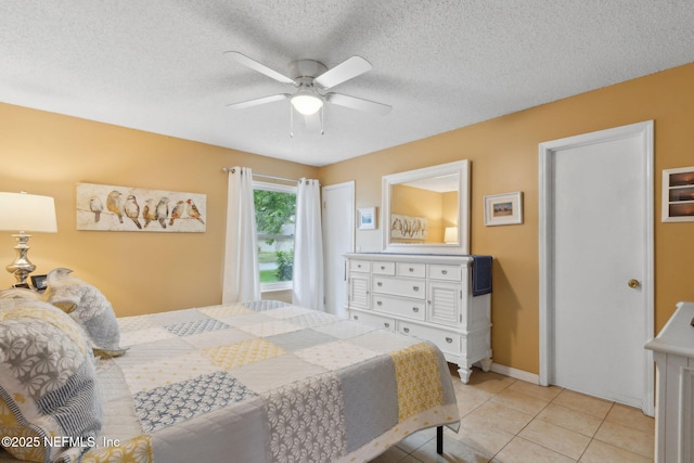 bedroom featuring baseboards, light tile patterned floors, ceiling fan, and a textured ceiling