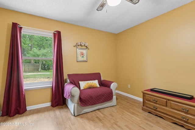 living area with baseboards, a ceiling fan, and light wood finished floors