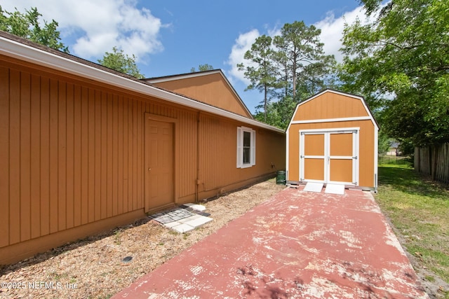 view of side of home with fence, a patio area, a shed, and an outbuilding