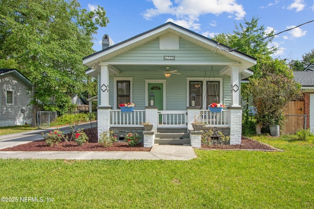 view of front of property featuring covered porch, fence, a chimney, and a front yard