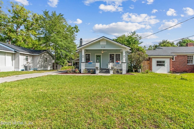 bungalow-style house with a porch, a front yard, cooling unit, a chimney, and concrete driveway