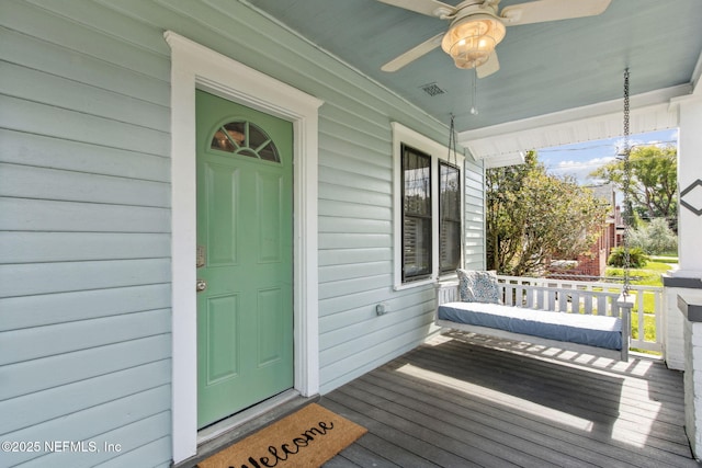 view of exterior entry featuring a porch, ceiling fan, and visible vents
