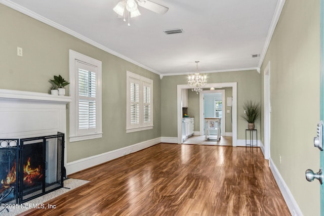 unfurnished living room featuring a fireplace with flush hearth, crown molding, visible vents, wood finished floors, and ceiling fan with notable chandelier