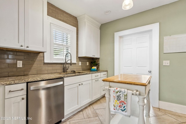kitchen with light stone countertops, a sink, tasteful backsplash, dishwasher, and white cabinets