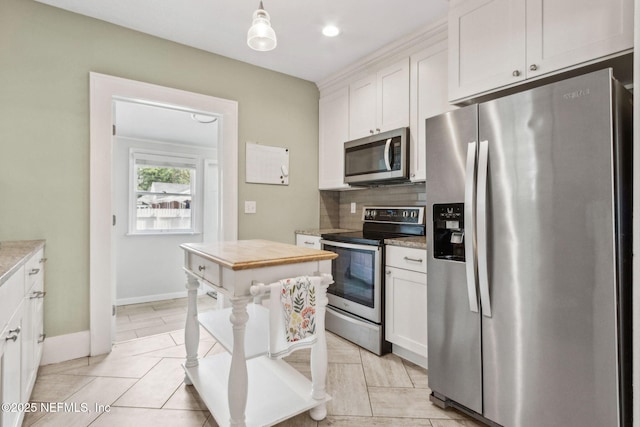kitchen with appliances with stainless steel finishes, white cabinetry, decorative backsplash, and baseboards