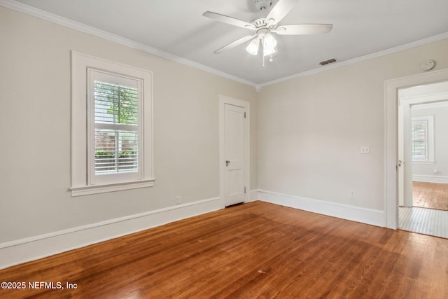 empty room with crown molding, baseboards, wood finished floors, and a healthy amount of sunlight