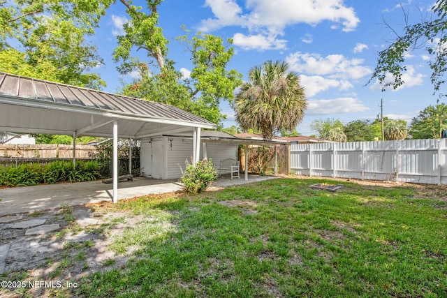 view of yard with a carport, a fenced backyard, and a patio area