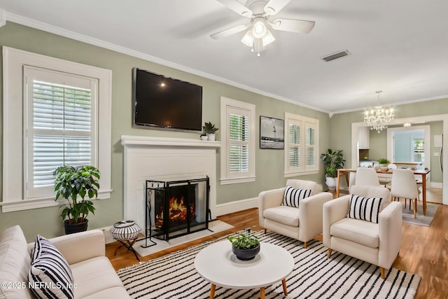 living area with visible vents, a fireplace with flush hearth, wood finished floors, and plenty of natural light