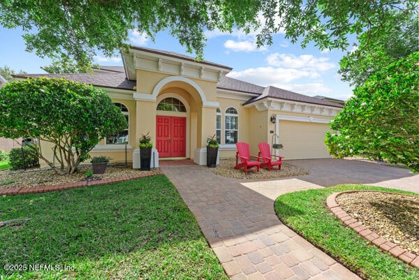mediterranean / spanish home featuring stucco siding, a front yard, aphalt driveway, and a garage