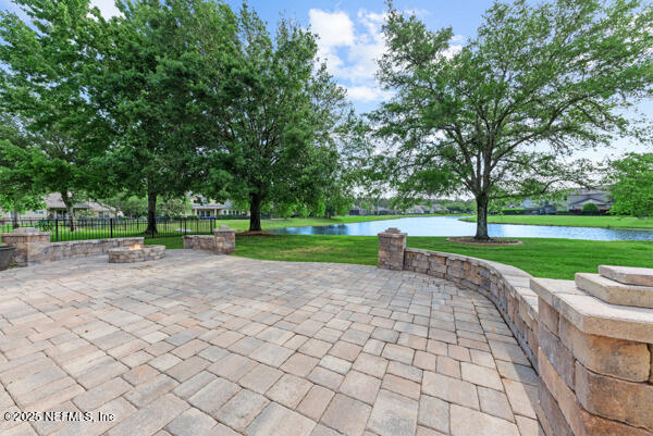 view of patio / terrace with fence, a fire pit, and a water view