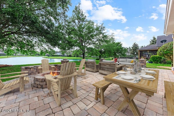 view of patio with an outdoor living space with a fire pit and a water view