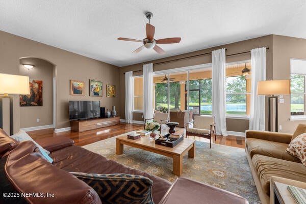 living room with wood finished floors, a ceiling fan, and baseboards