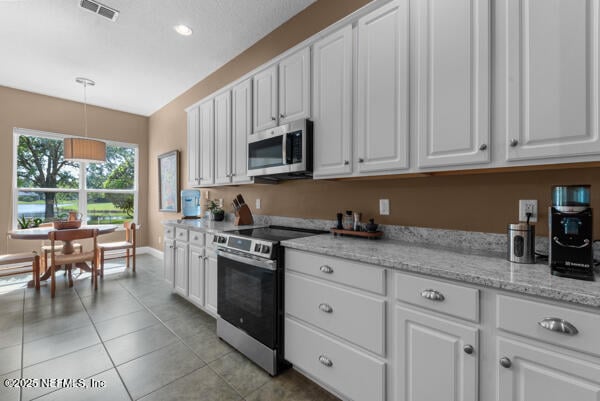 kitchen featuring range with electric cooktop, stainless steel microwave, visible vents, and white cabinets