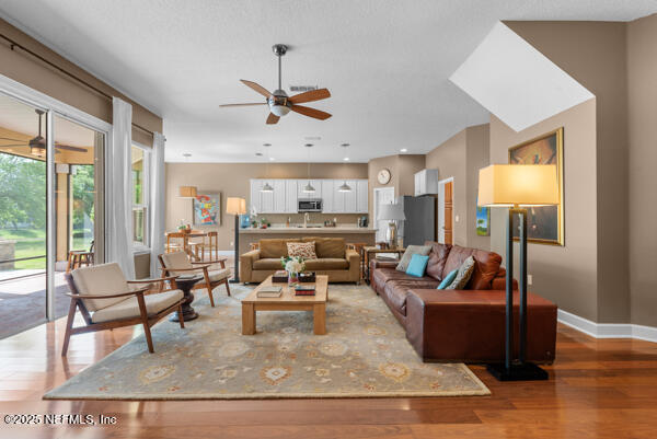 living room with a ceiling fan, baseboards, and light wood-style floors