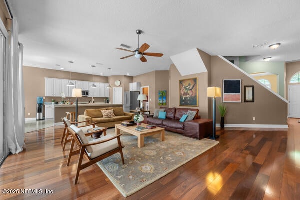 living area featuring wood finished floors, a ceiling fan, and baseboards